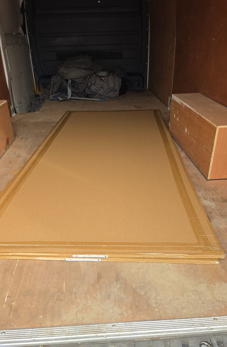 A large wooden door lying flat in the load area of a van
