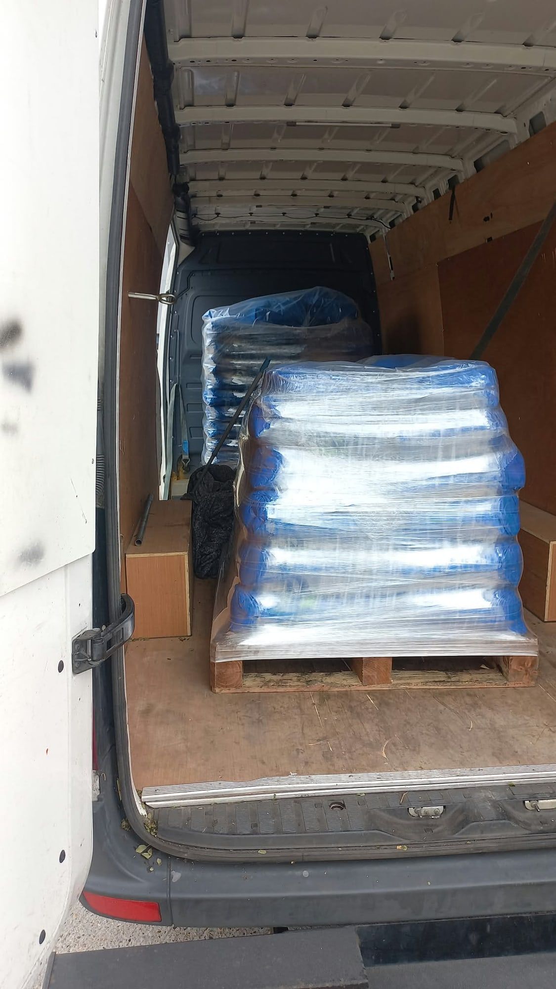Two pallets of blue wrapped goods inside a long wheelbase van